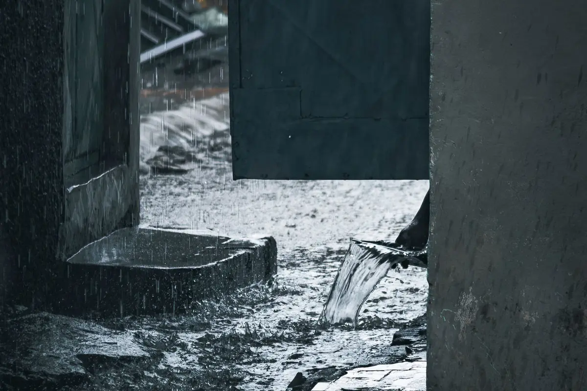 Rainwater pouring past an open doorway during a storm