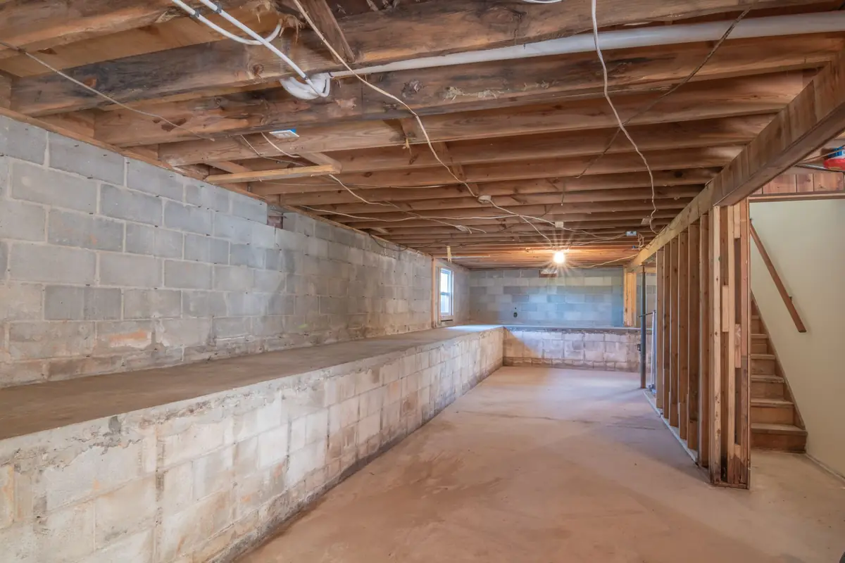 An unfinished basement with block walls and exposed wooden joists