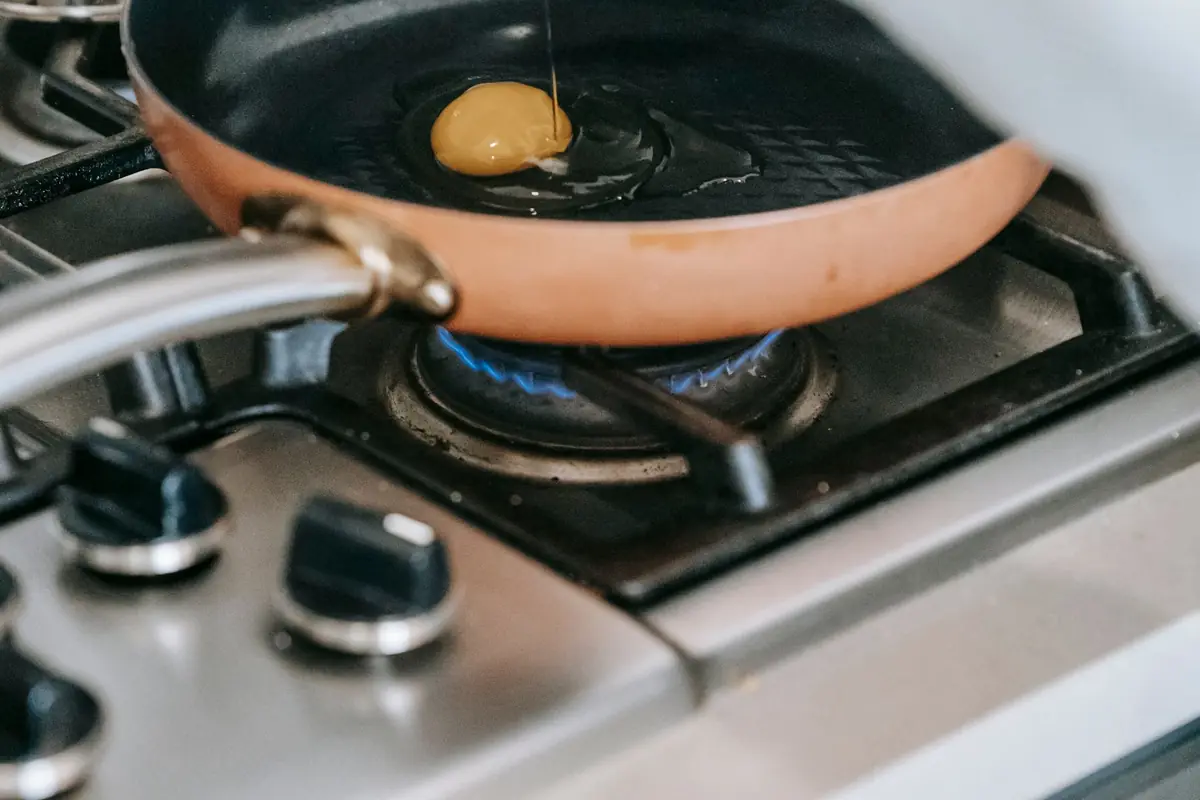 Cracking an egg into a frying pan on a gas stove