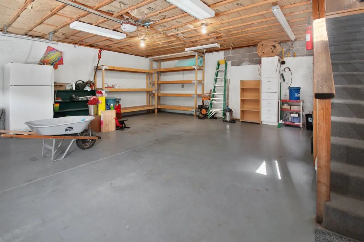 A clean two-car garage with storage shelves and a white refrigerator against the back wall