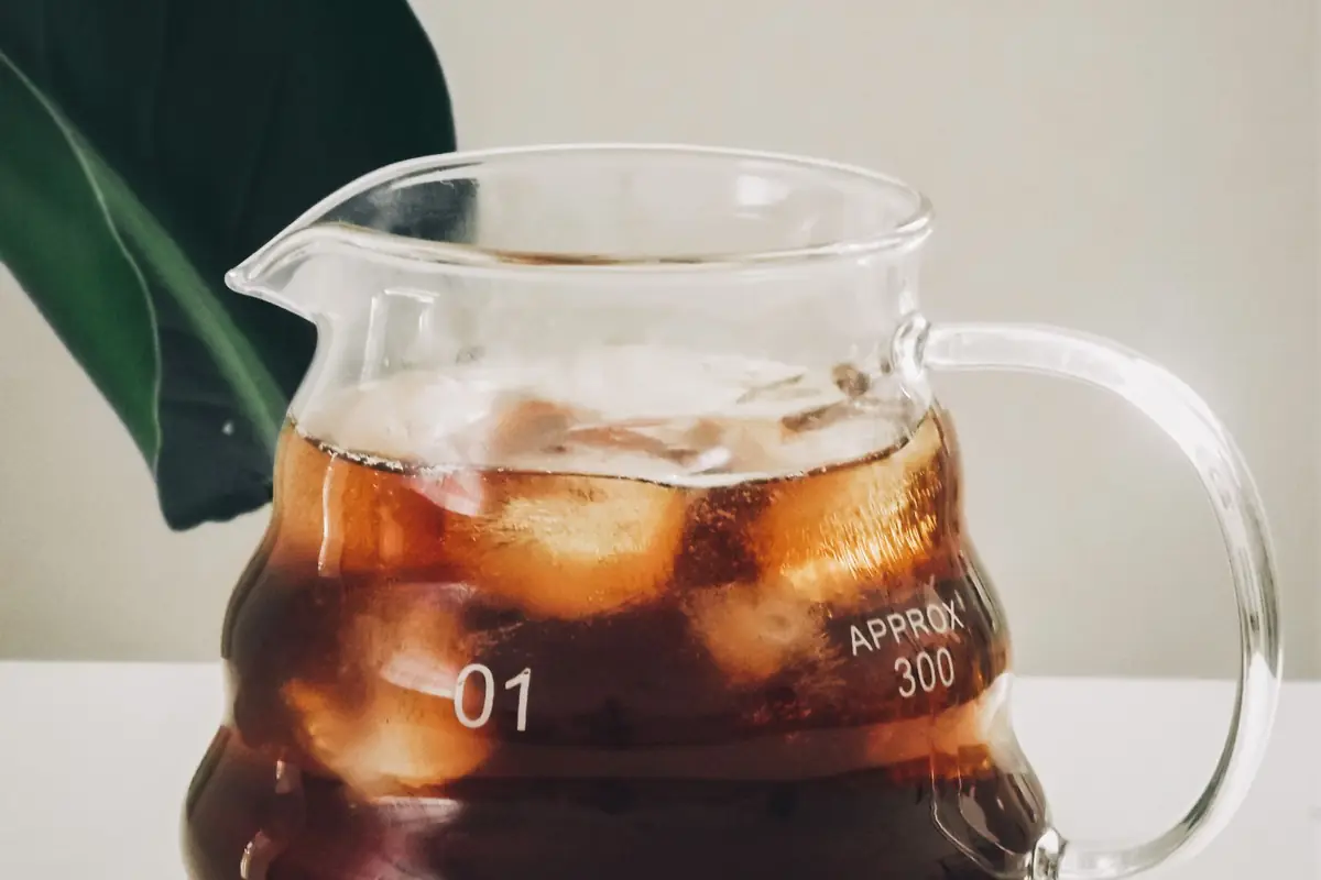 A pitcher of iced coffee next to a filled glass