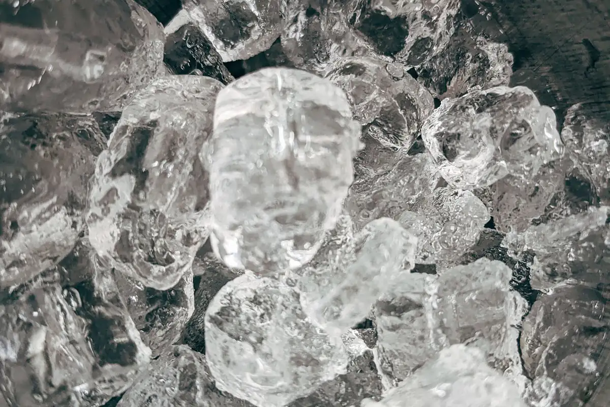 A metal bowl full of clear ice cubes