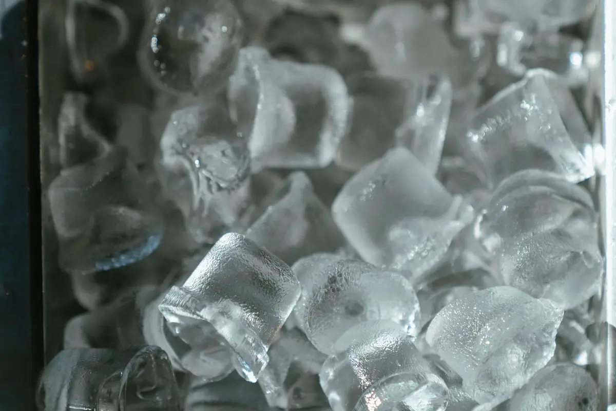 Clear ice cubes piled in a metal tray