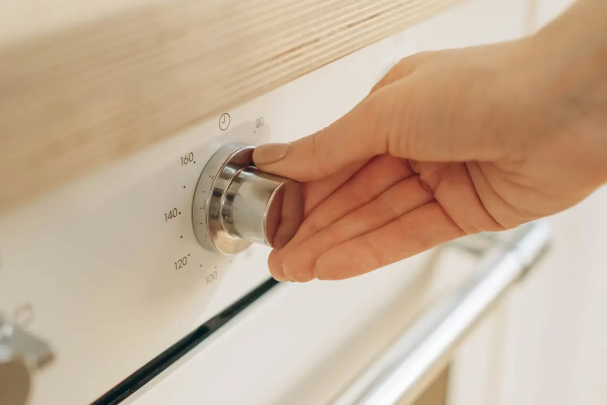 A hand turning an oven temperature dial