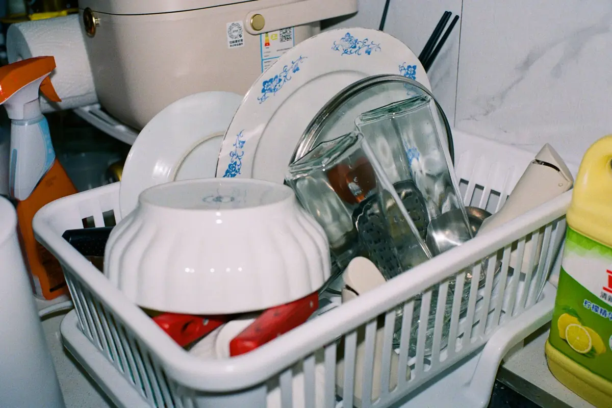 A white plastic dish rack crowded with bowls, plates and glasses
