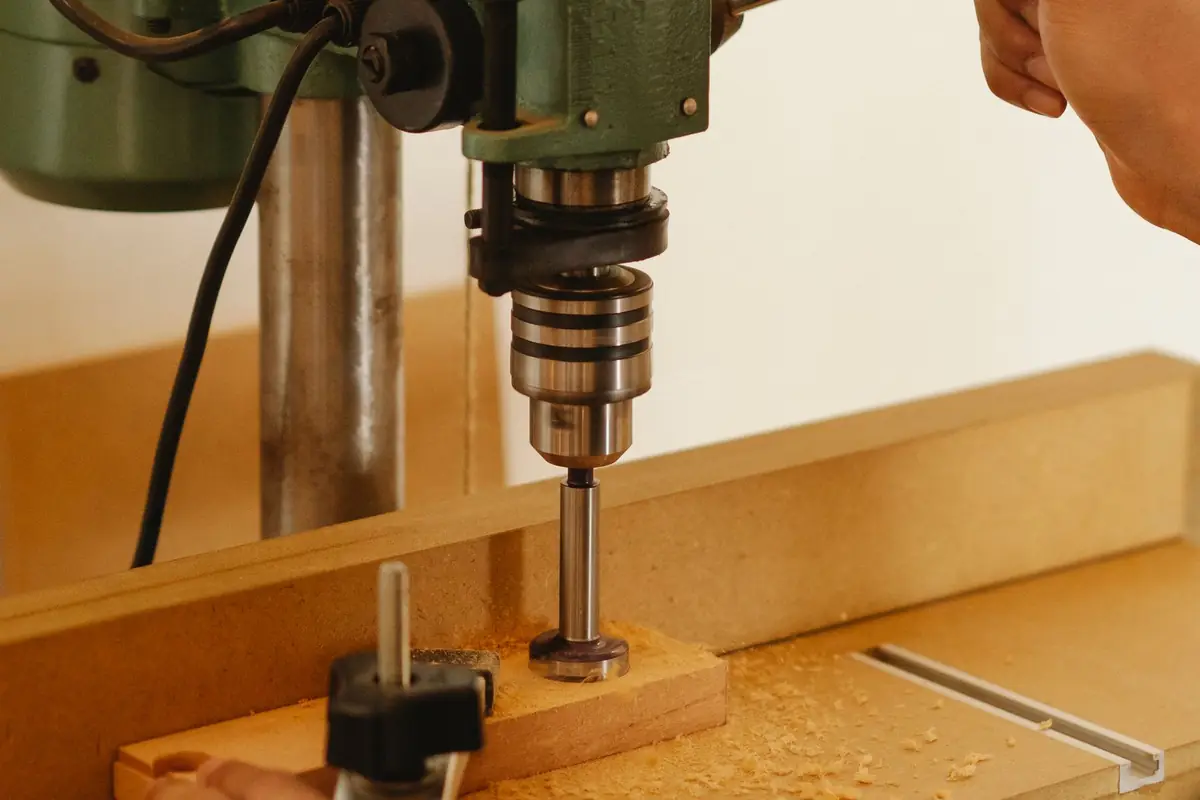 A benchtop drill press boring a hole in a wooden block