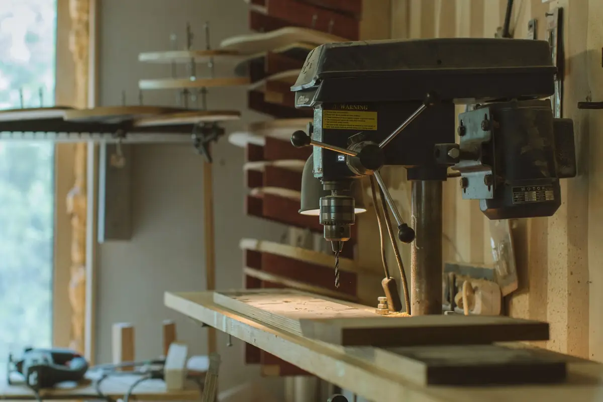 A drill press on a bench in a home woodworking shop