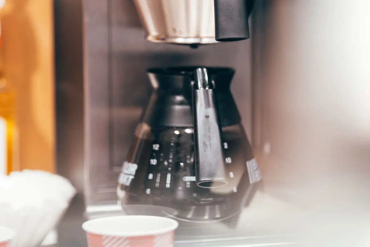 A drip coffee maker brewing coffee into a glass carafe