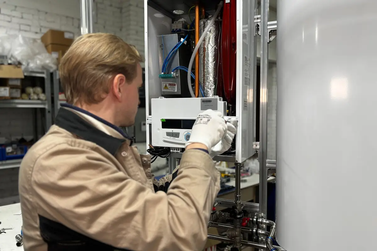 A technician servicing a wall-mounted water heating unit