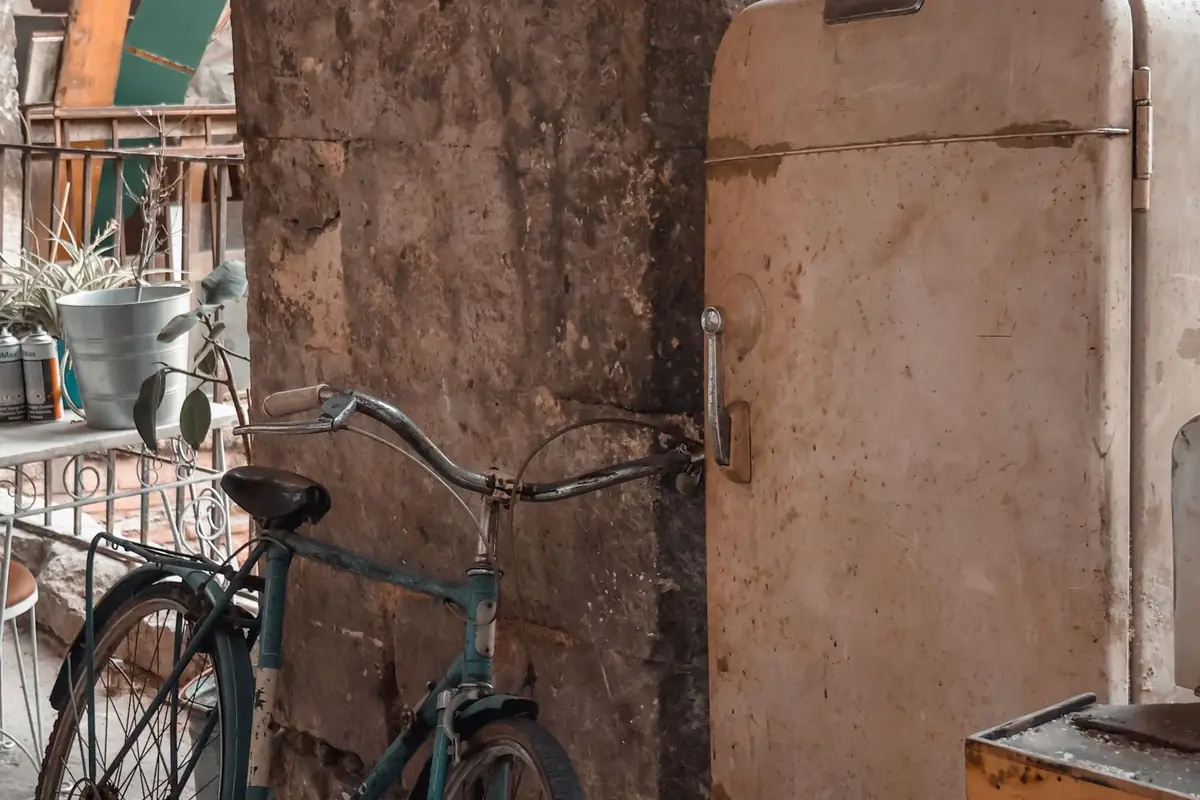 An old refrigerator next to a bicycle in a rustic workshop