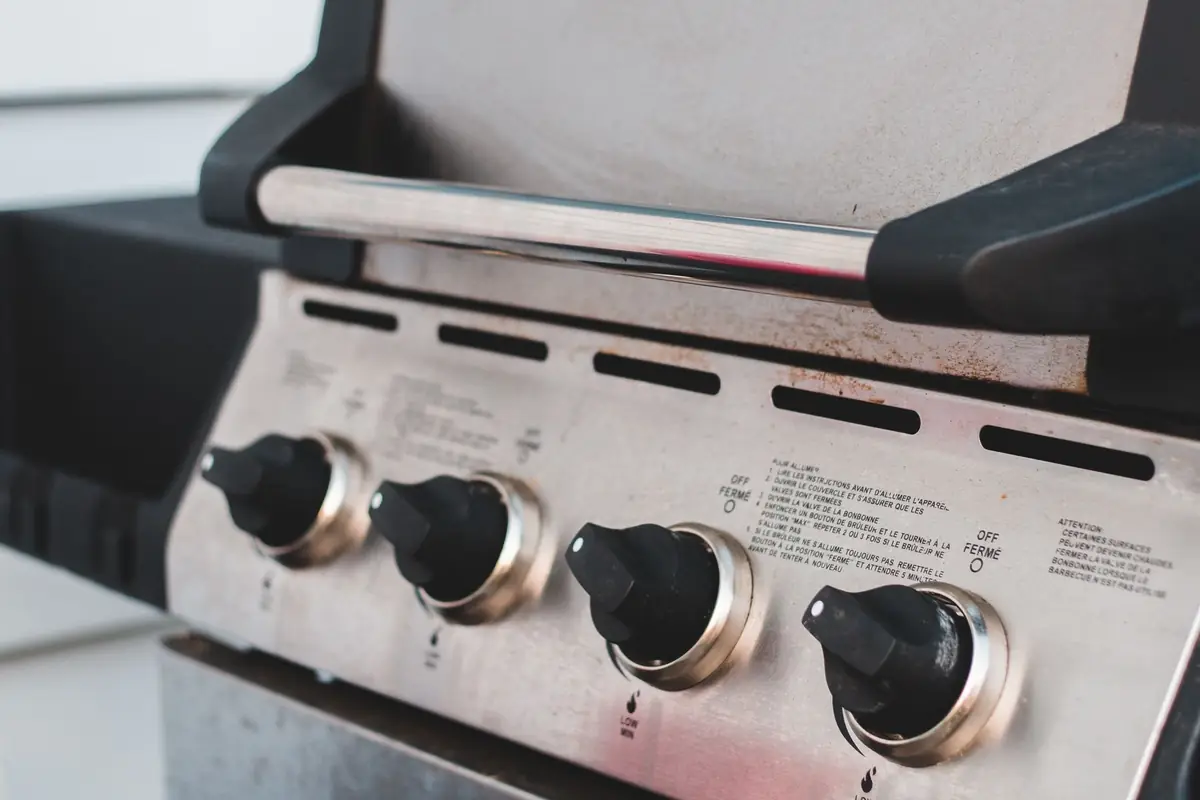 The four burner control knobs on a stainless steel gas grill