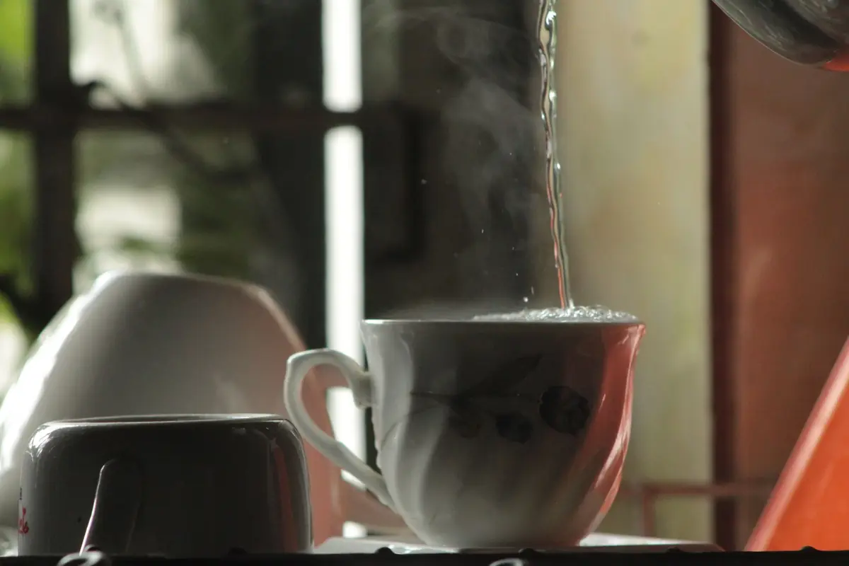 Steaming hot water poured into a ceramic teacup
