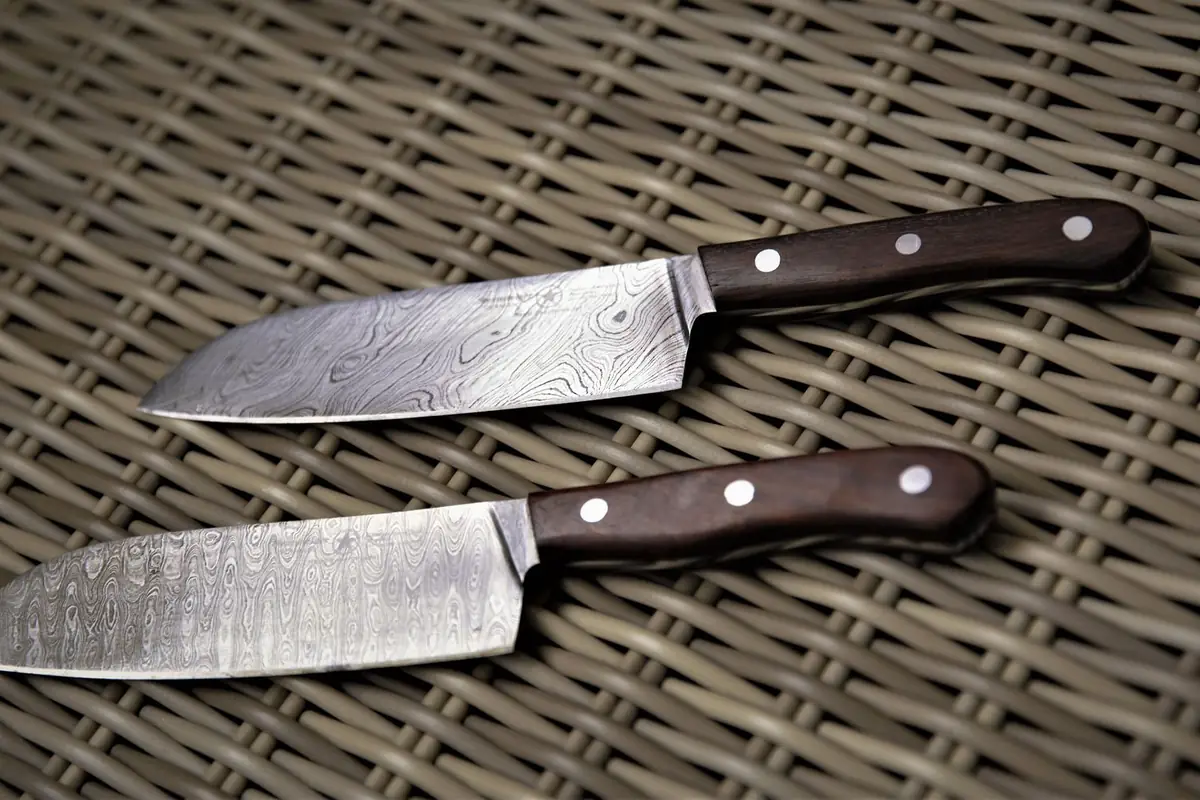 Two patterned steel knives with wooden handles