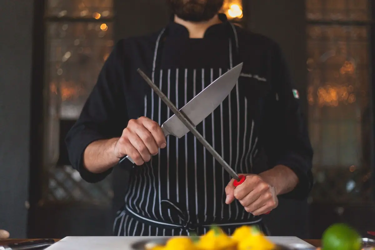 A cook running a knife along a honing rod