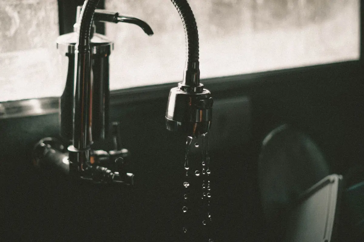 Water dripping from a dark pull-down faucet spray head