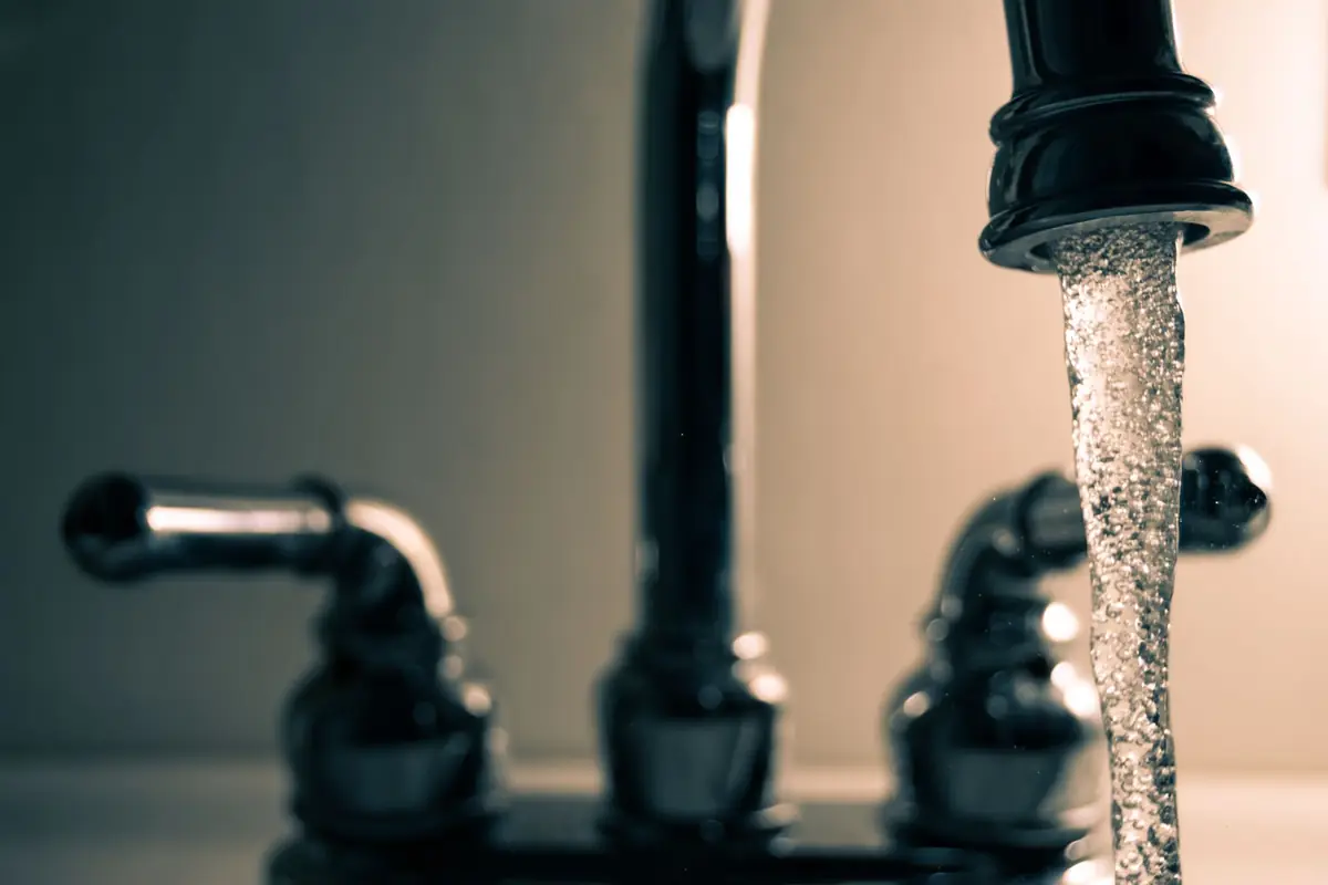 A stream of water pouring from a black faucet
