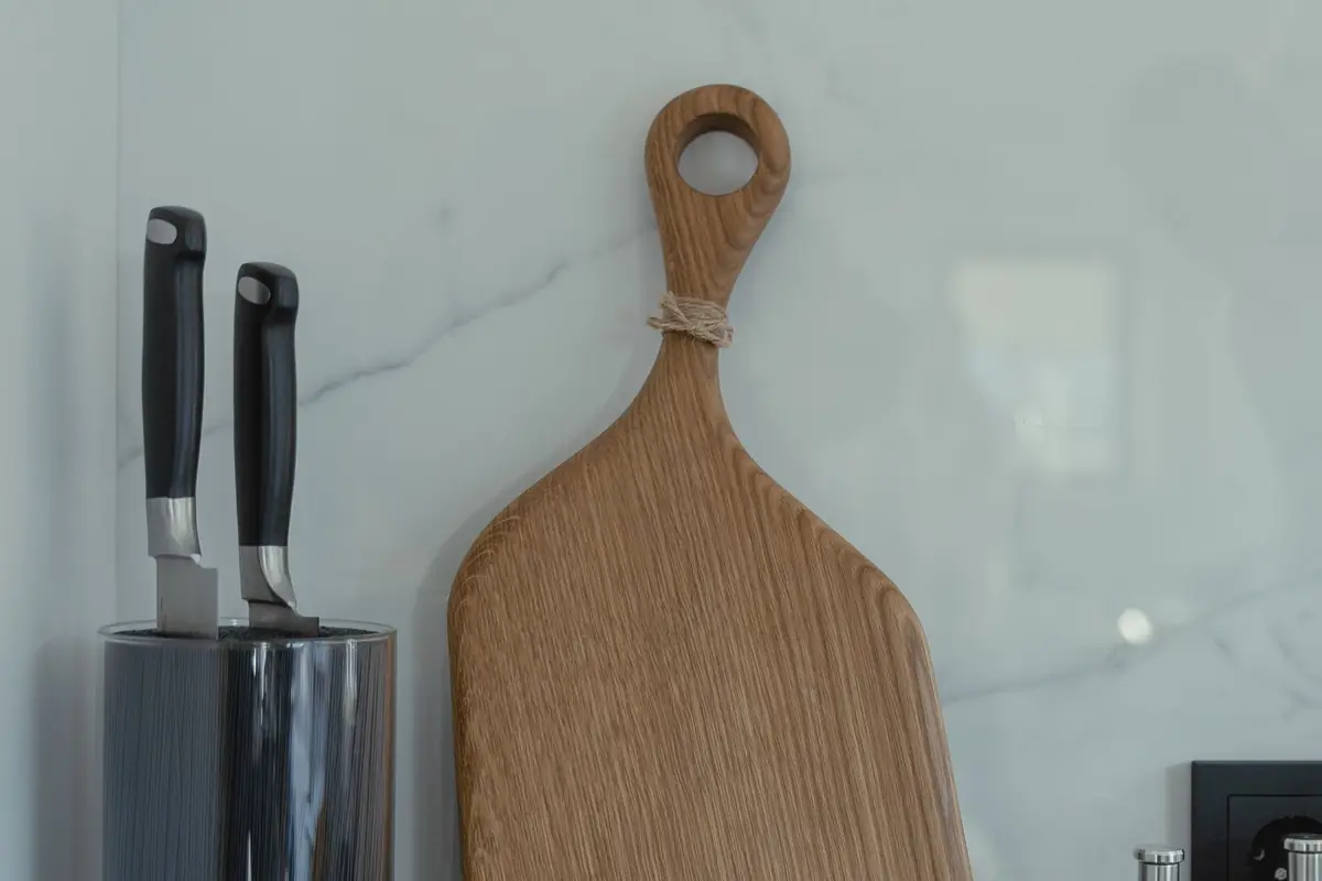 Kitchen knives in a holder beside a wooden cutting board on a marble counter