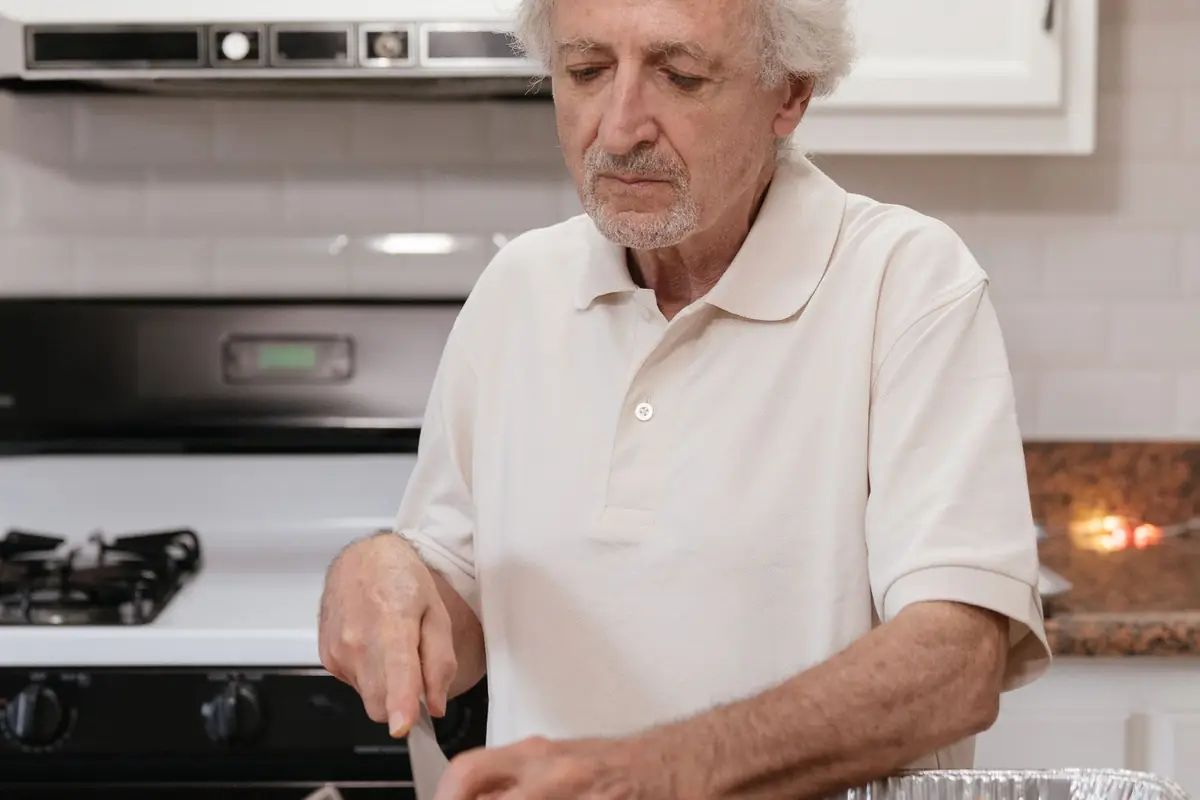 An older man preparing vegetables at a kitchen counter
