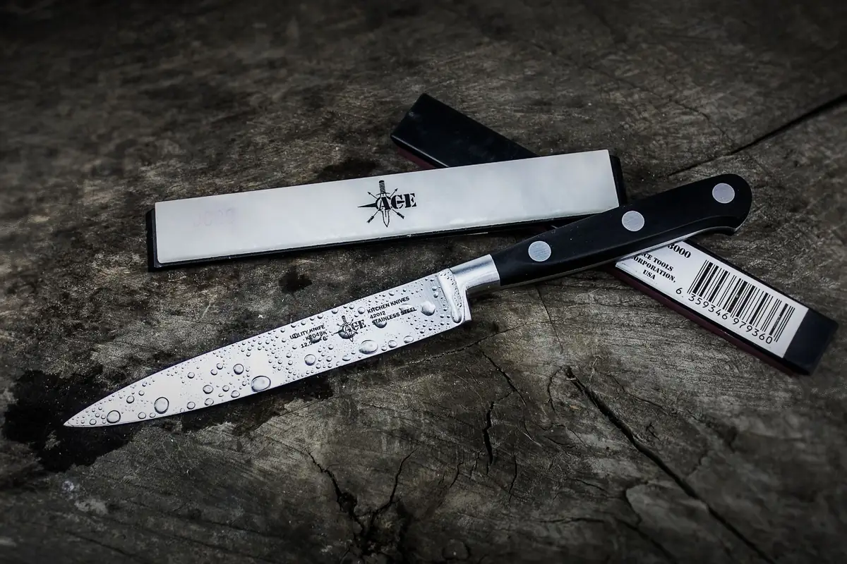 A chef's knife with water droplets on the blade beside its blade guard