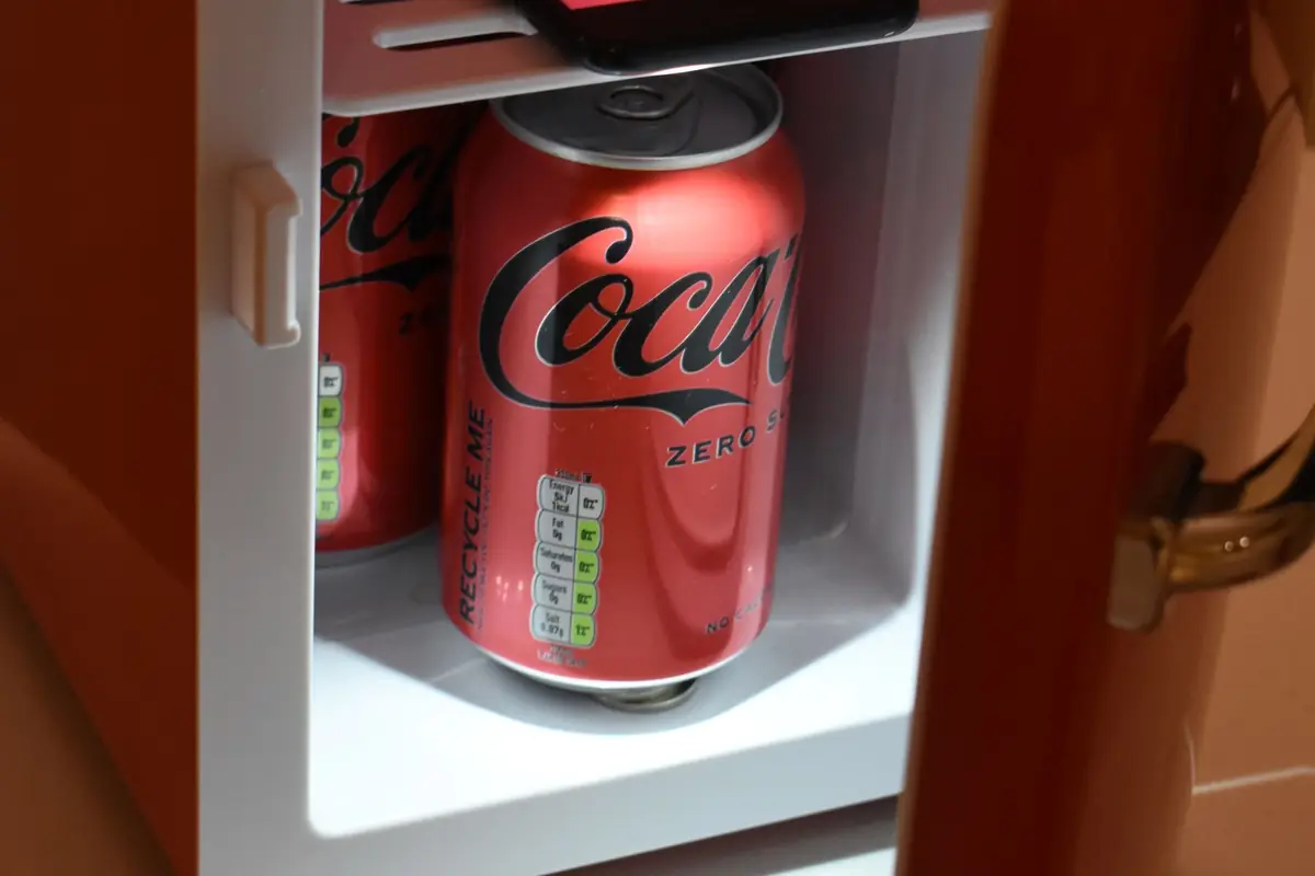 Cans of soda inside an open mini fridge