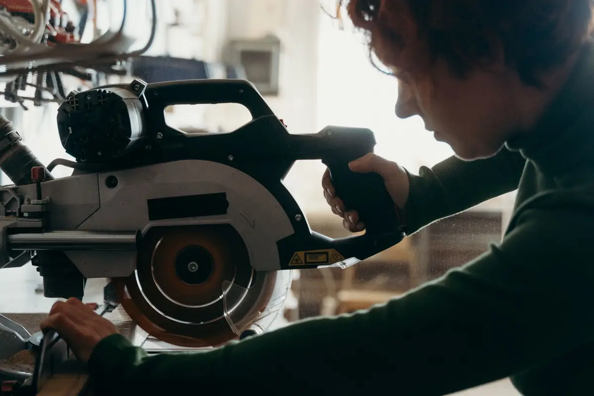 A woodworker lowering a power saw blade into a board