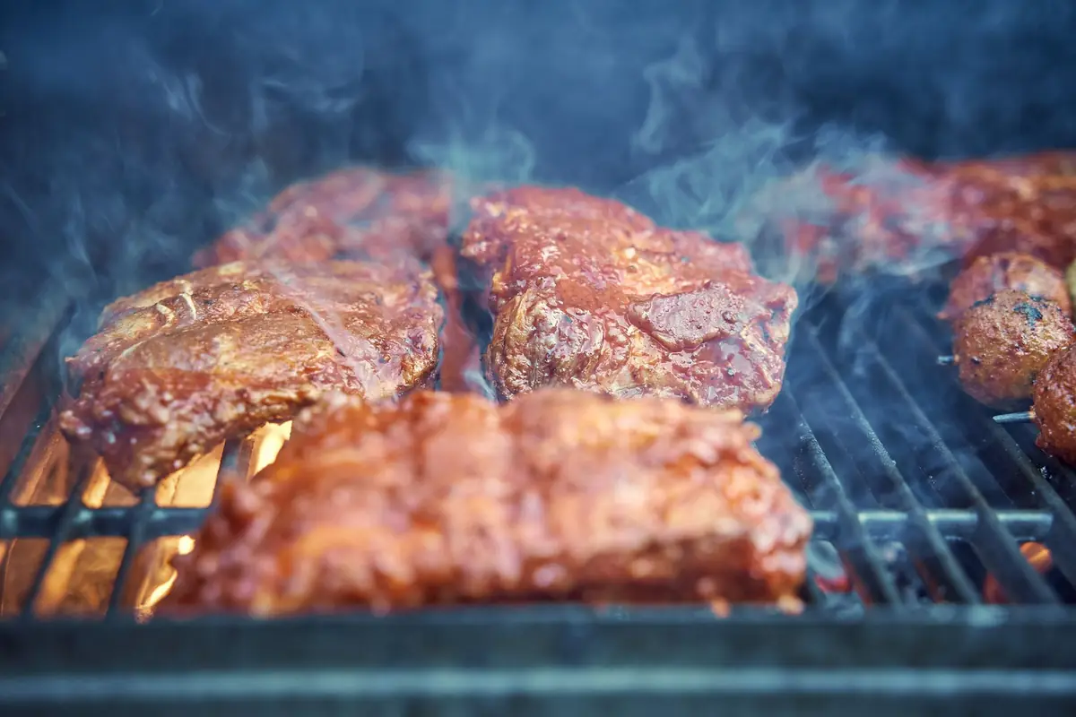 Racks of barbecue ribs over a hot grill