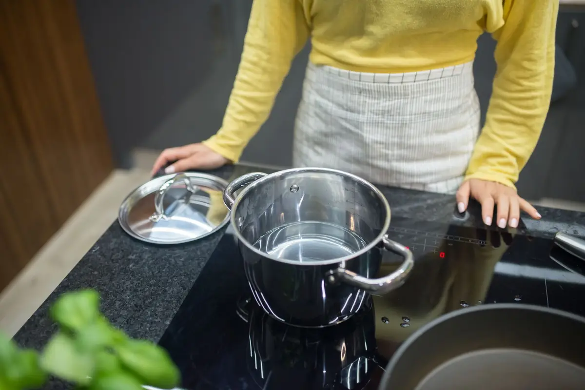 A cook with stainless steel pots on an induction cooktop