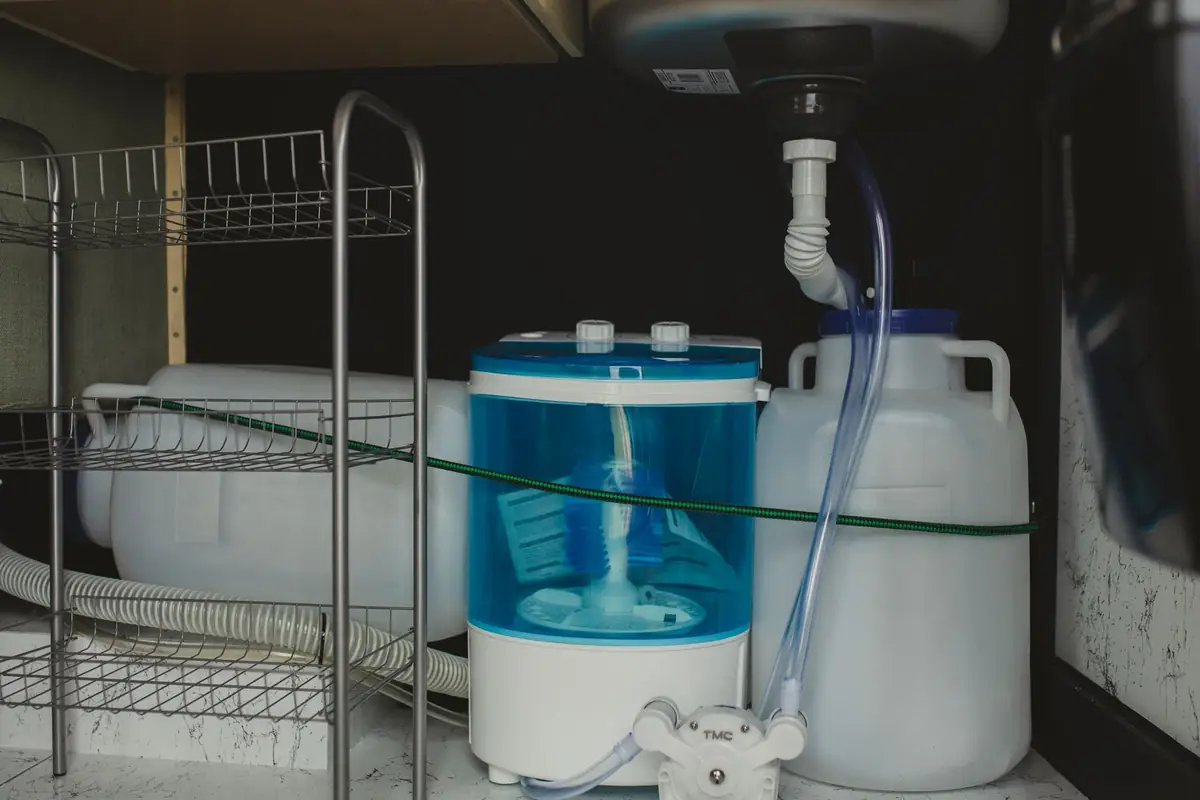 A compact portable washer with a water jug and hose in a storage area
