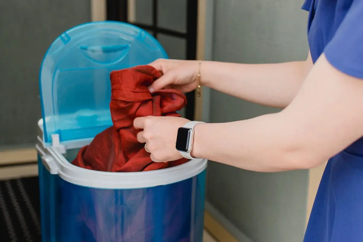 A person loading a shirt into a small portable washing machine