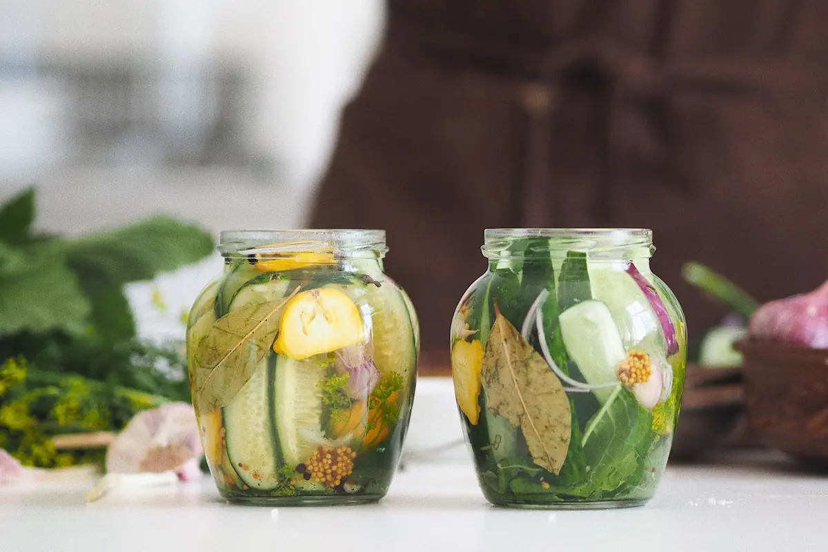 Two jars of pickled cucumbers with herbs