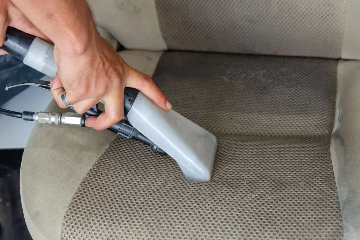 Cleaning a fabric car seat with an upholstery attachment
