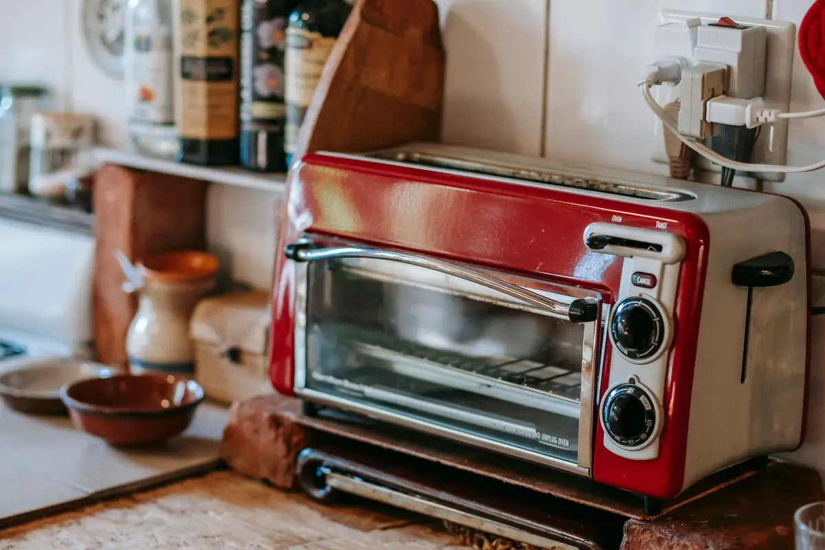 A red toaster oven on a wooden kitchen counter