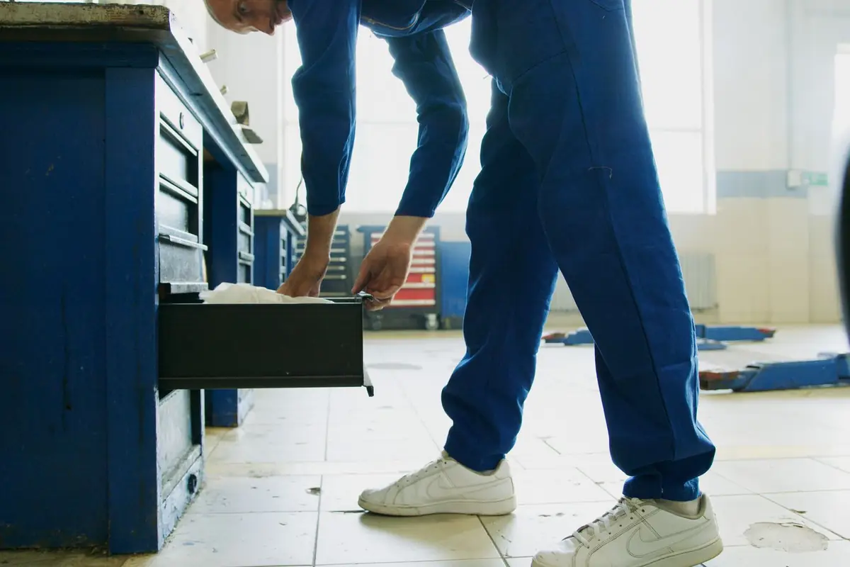 A mechanic opening a drawer of a rolling tool cabinet in a garage