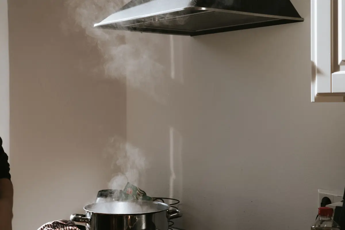 Steam rising from a pot toward a stainless range hood