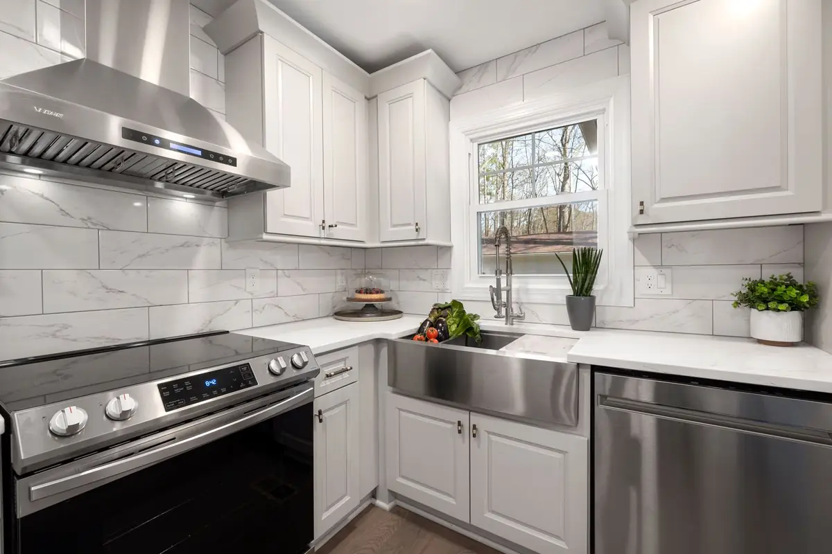 A white kitchen with a stainless under-cabinet range hood over an electric range