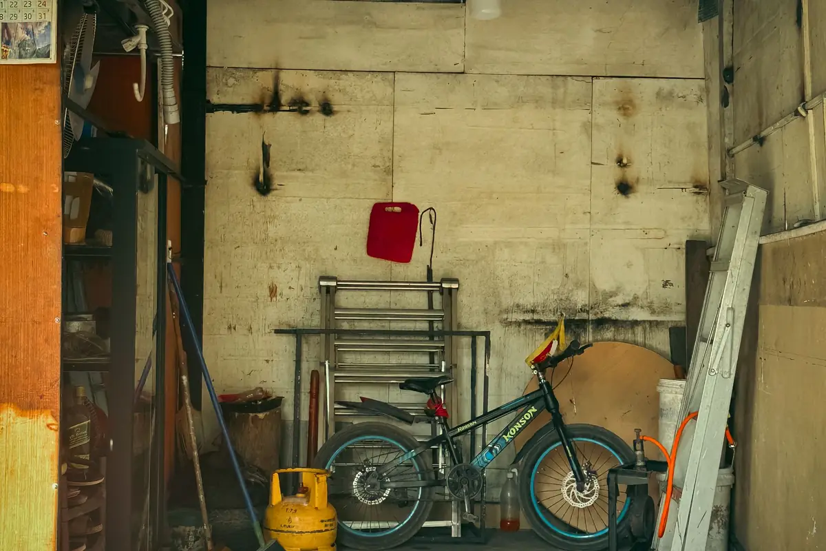 A tidy garage with a bicycle, a ladder and tools along the wall