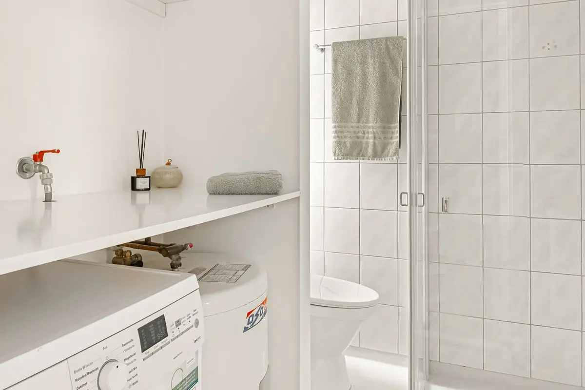 Laundry machines tucked under a counter in a small white bathroom