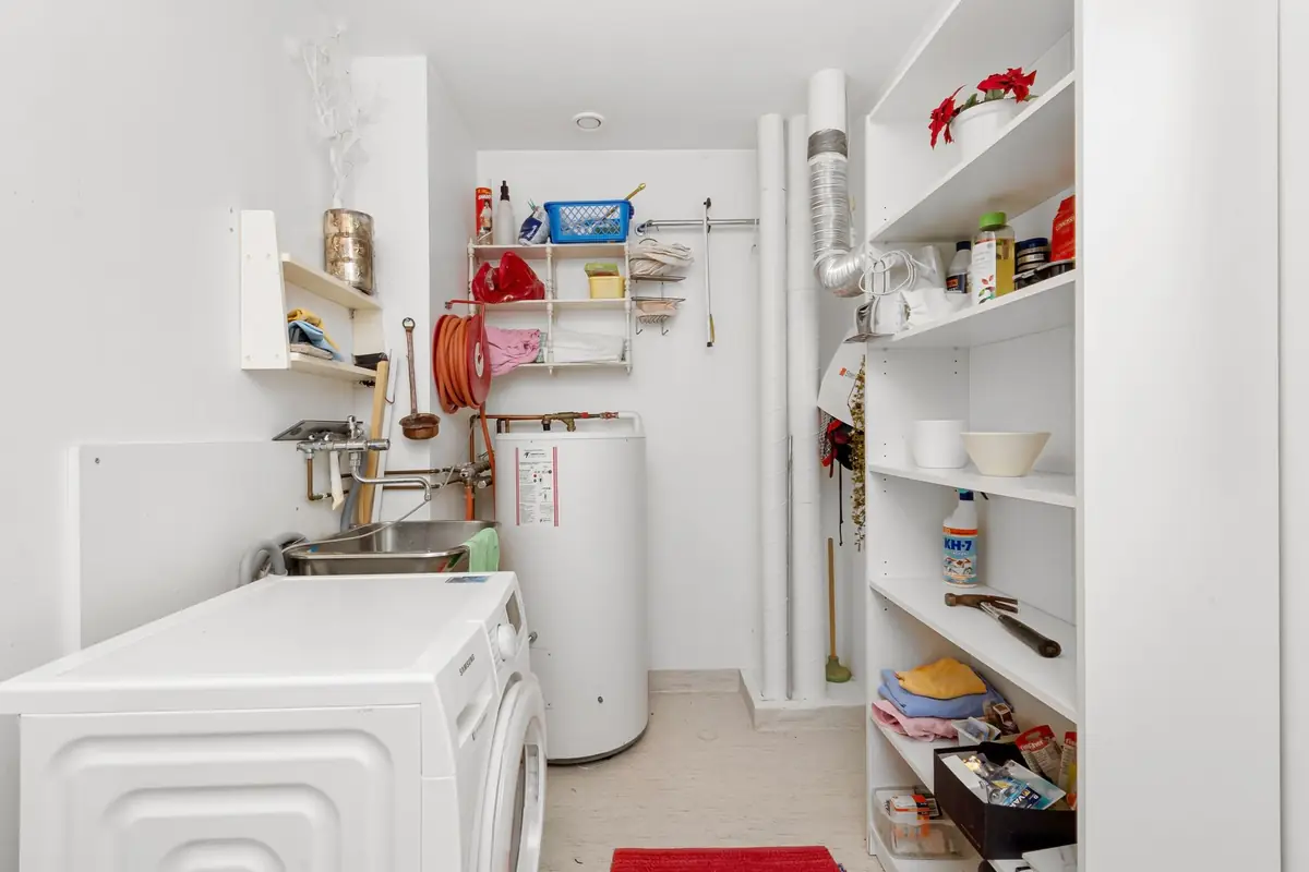 A small laundry room with a washing machine and a water heater