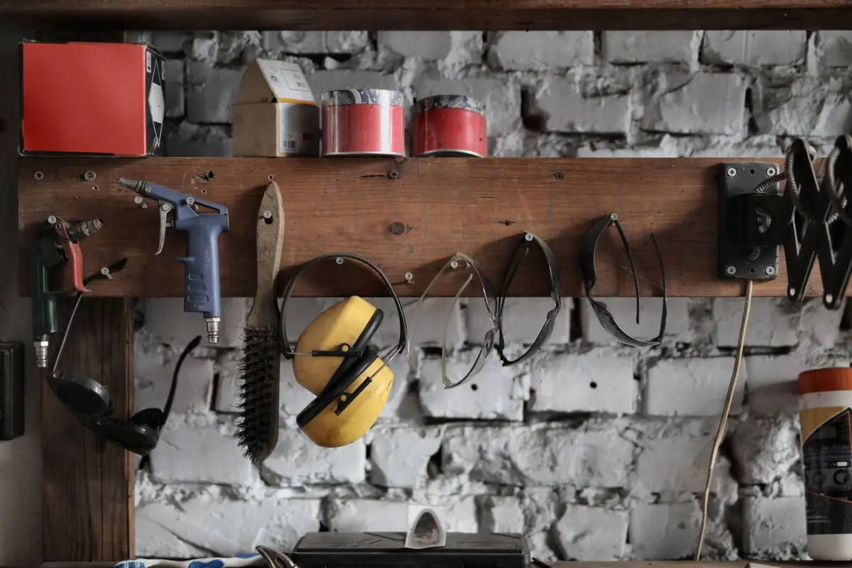 Tools and ear protection hanging on a wooden board over a workbench