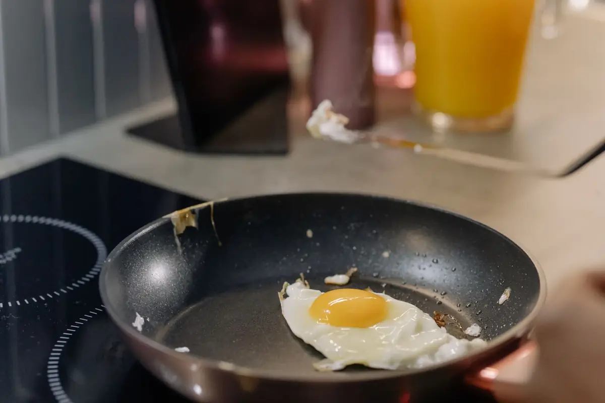 An egg frying in a nonstick pan on an induction cooktop