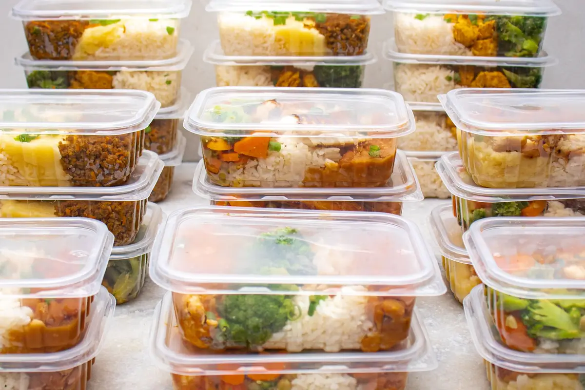 Stacked meal prep containers of rice and vegetables ready for the freezer