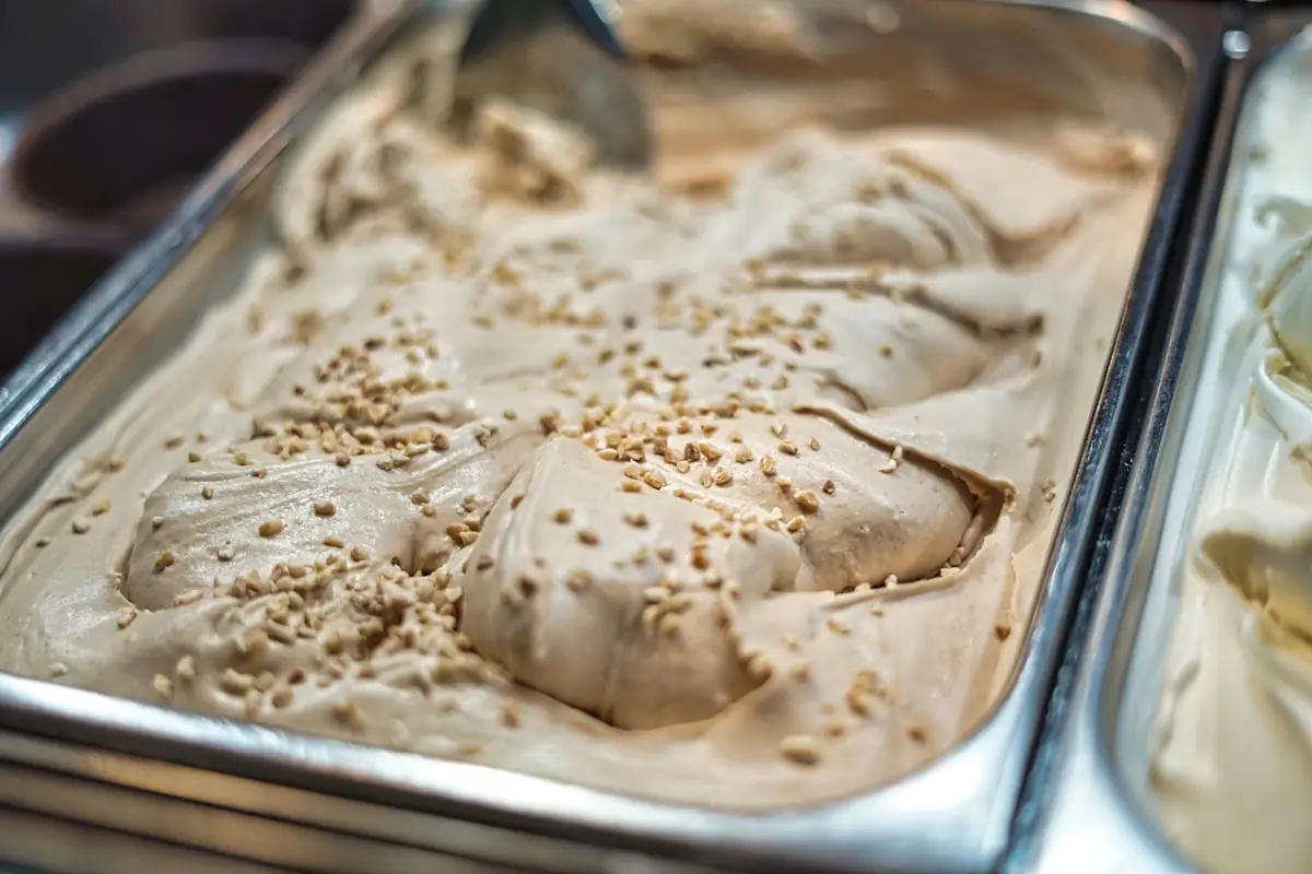 Gelato topped with chopped nuts in a metal tray