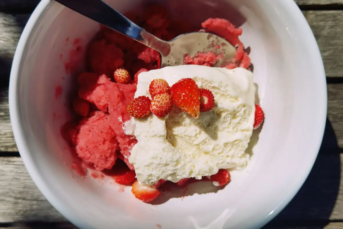 A bowl of homemade strawberry ice cream topped with fresh strawberries