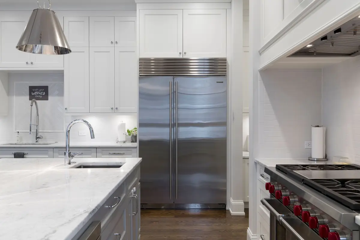 A white kitchen with a built-in stainless steel refrigerator