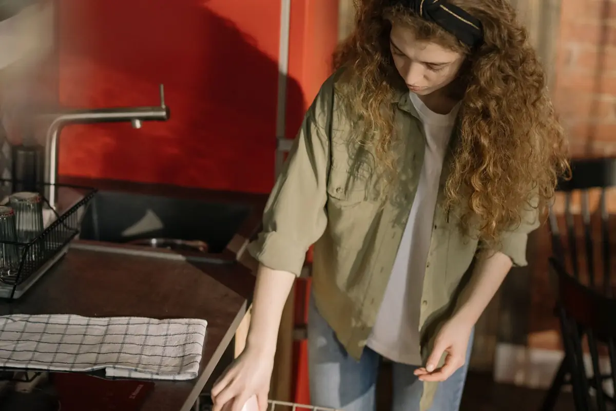 A woman pulling out the lower rack of a dishwasher