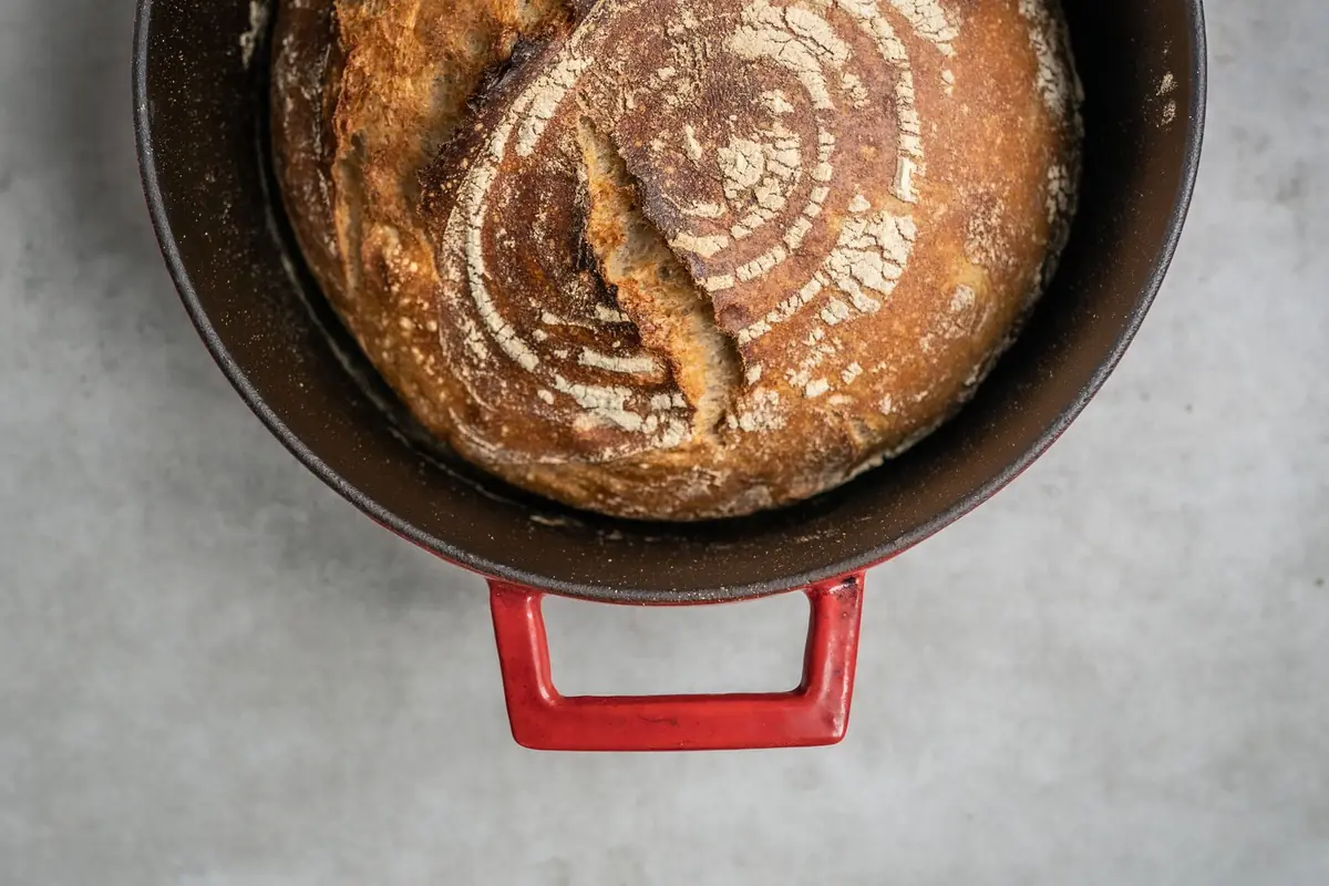 A loaf of bread baked in a red enameled Dutch oven