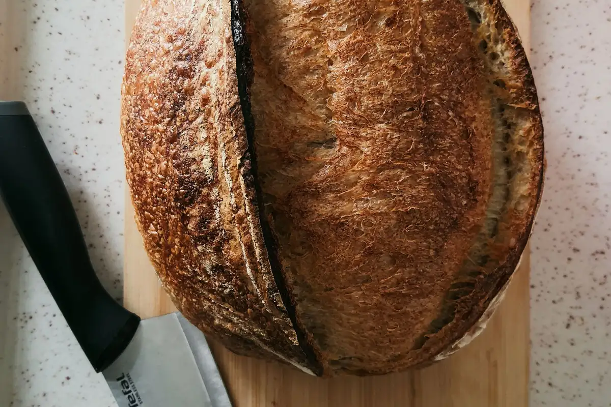 A crusty sourdough loaf on a wooden cutting board