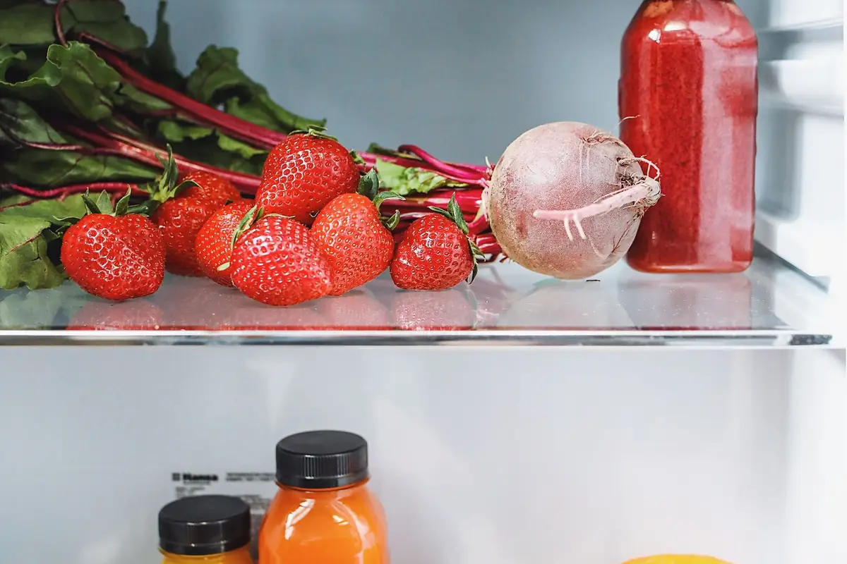 Fresh strawberries, chard and drinks on a refrigerator shelf