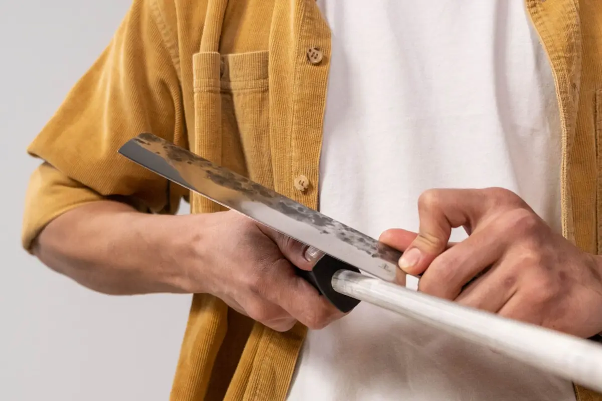 A man running a chef's knife along a honing rod