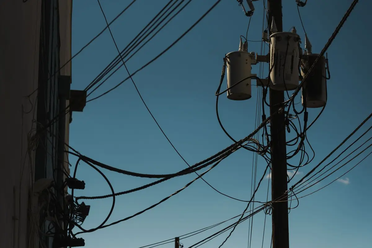 Power lines and transformers on a utility pole against a blue sky